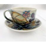 A Moorcroft cup & saucer decorated with brambles (blackberries & leaves) impressed & monogrammed (