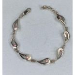 A modern silver designer bracelet with teardrop links set with pink stones