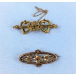 A carat hallmarked gold oval brooch decorated with flowers; a 9 carat twin heart bar brooch with