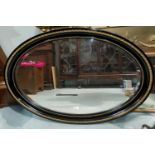 A large wall mirror in oval ebonised and gilded frame, length 106 cm