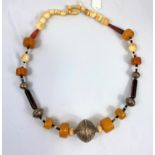 An ethnic necklace formed from large beads of amber coloured material .....