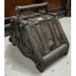 An Arts and Crafts oak and metal bound coal scuttle designed in the manor of Christopher Dresser