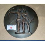 A bronze circular medallion depicting 2 female archers in relief, Moscow Olympics logo on the