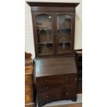 An early 20th century oak bureau/bookcase with twin glazed doors, fall front, and 3 drawers below