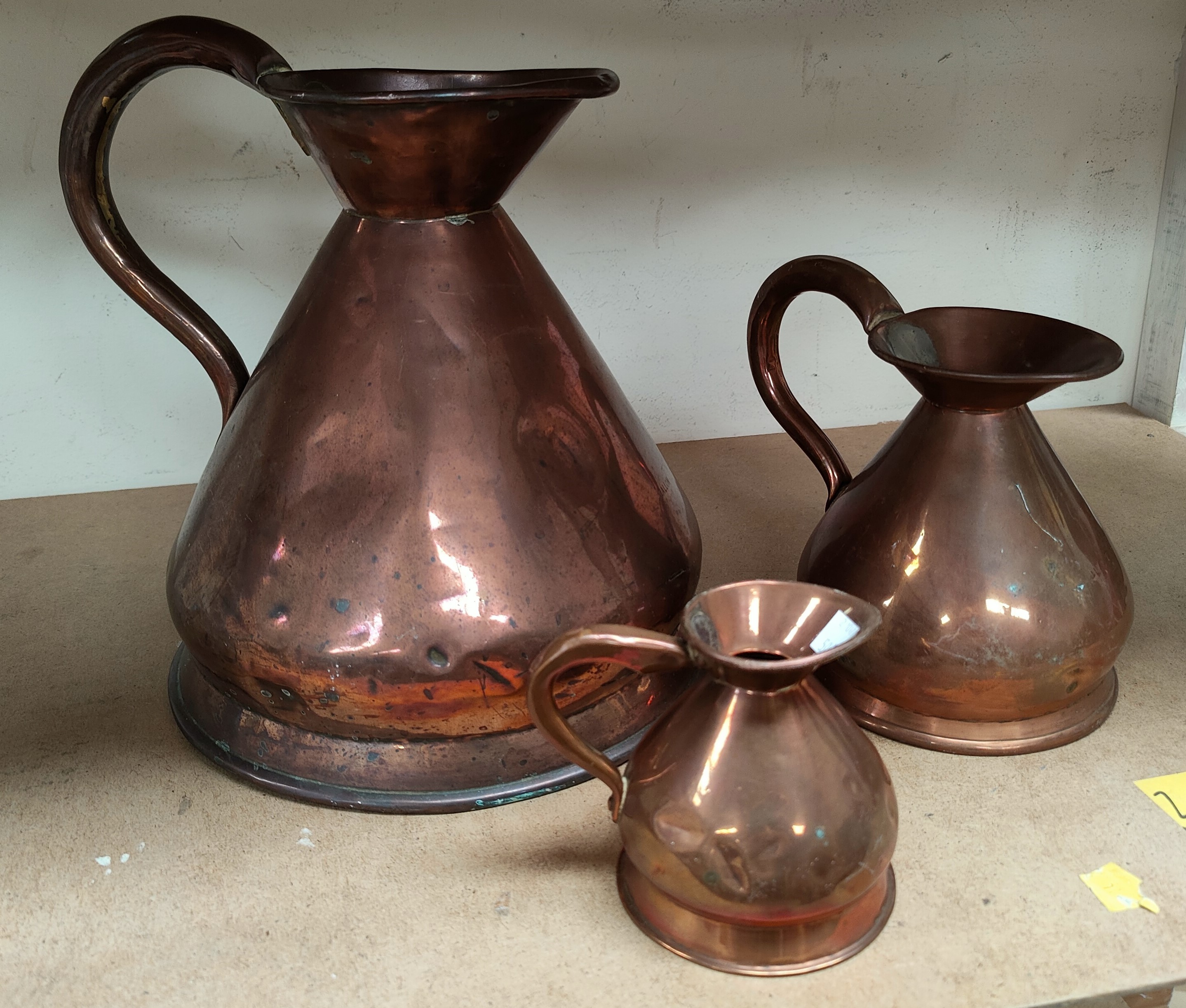 A 19th century matched set of three graduating copper measuring jugs, the smaller of the three