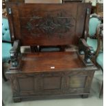 A late Victorian carved oak monk's bench with box seat and lion carved armrests