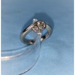 A white metal crossover ring set a large and a small diamond, stamped 'PT900', larger stone