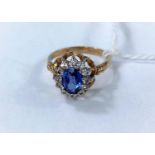 A 9 carat hallmarked gold dress ring set oval sapphire coloured stone, surrounded by clear stones,