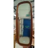 A mid century teak wall mirror in rounded rectangular elongated frame; an oval mirror in