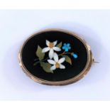 A vintage Pietra-Dora brooch showing blue and white flowers in a plain oval surround testing 9ct