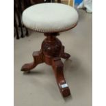A Victorian carved walnut piano stool with circular revolving top, on triple splay feet