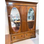 An Edwardian inlaid mahogany double wardrobe in the Sheraton style, with twin oval mirror doors