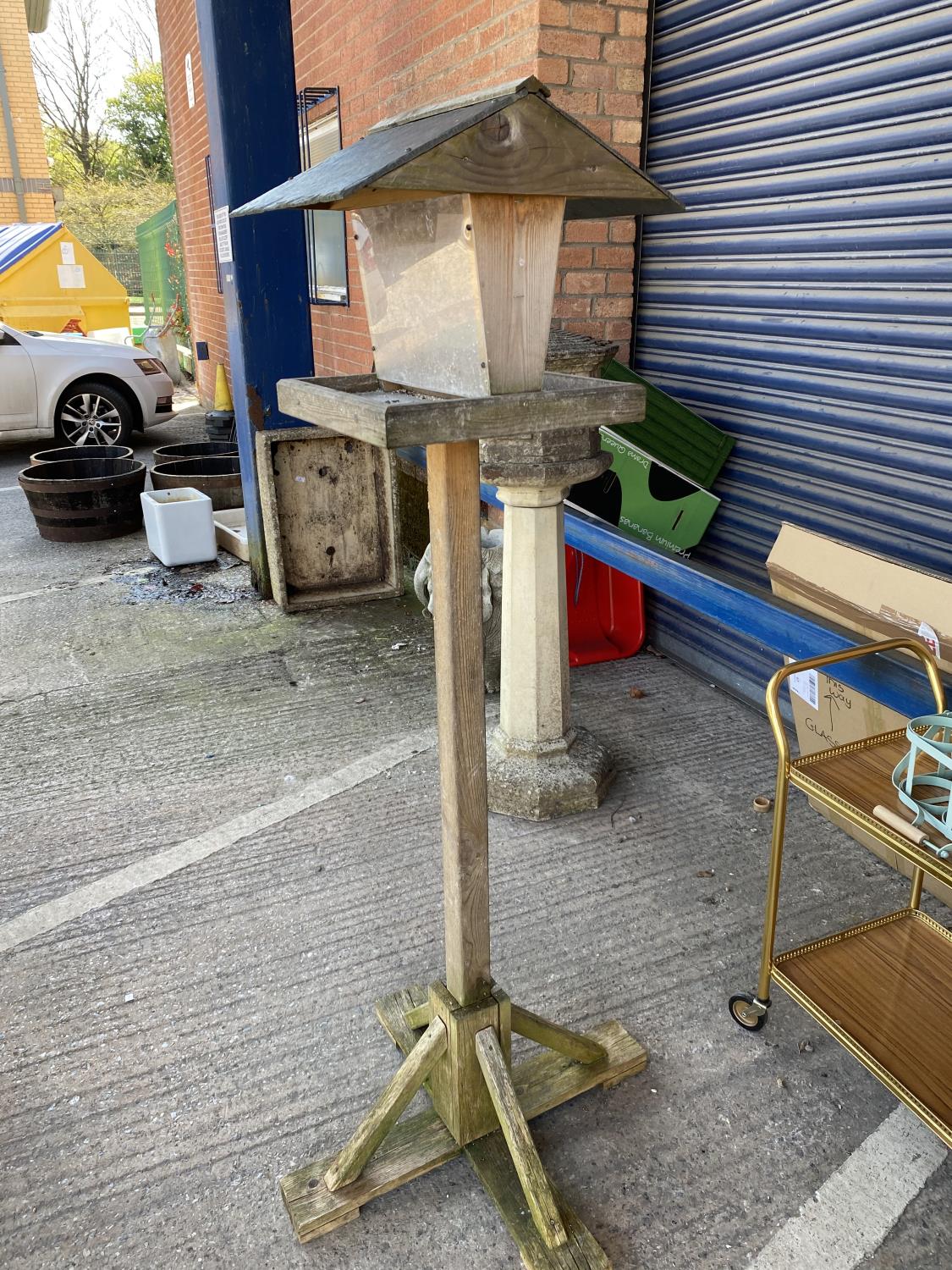 A wooden bird table with slate roof