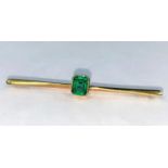 A yellow metal bar brooch stamped 15ct set with a rectangular cushion cut emerald coloured stone 3.