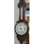 An Edwardian barometer with thermometer in carved oak case