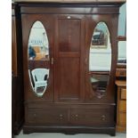 An Edwardian inlaid mahogany double wardrobe in the Sheraton style, with twin oval mirror doors