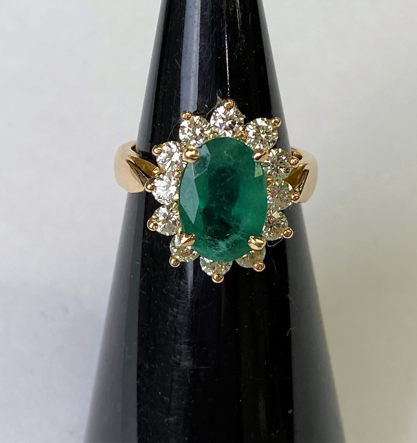 An 18ct gold dress ring set with a large faceted oval emerald, 11mm x 7mm and surrounded by 12 - Image 3 of 4