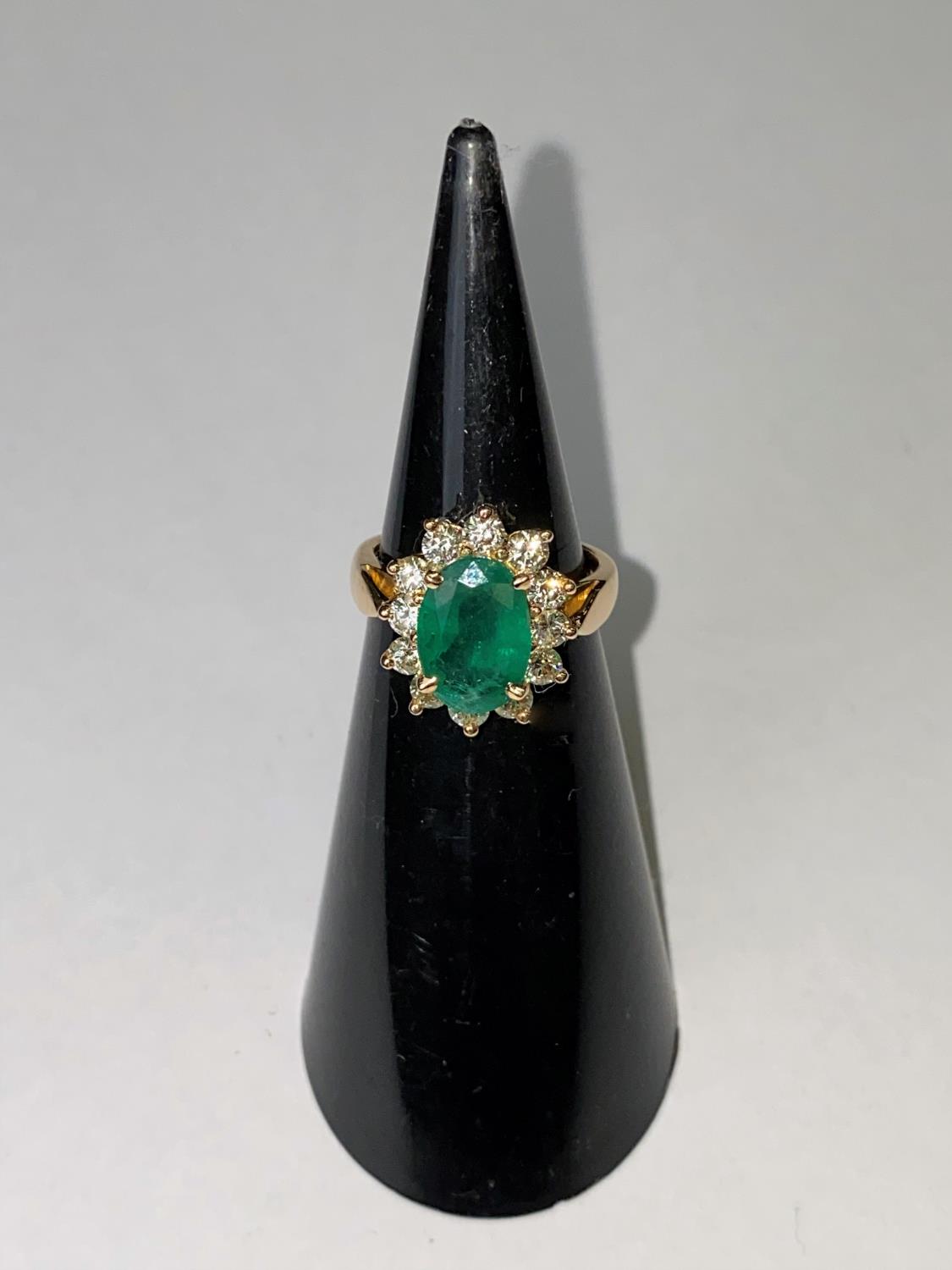 An 18ct gold dress ring set with a large faceted oval emerald, 11mm x 7mm and surrounded by 12 - Image 2 of 4
