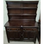 An Ercol dark oak Welsh dresser with 2 height delft rack over 2 cupboards and 2 drawers