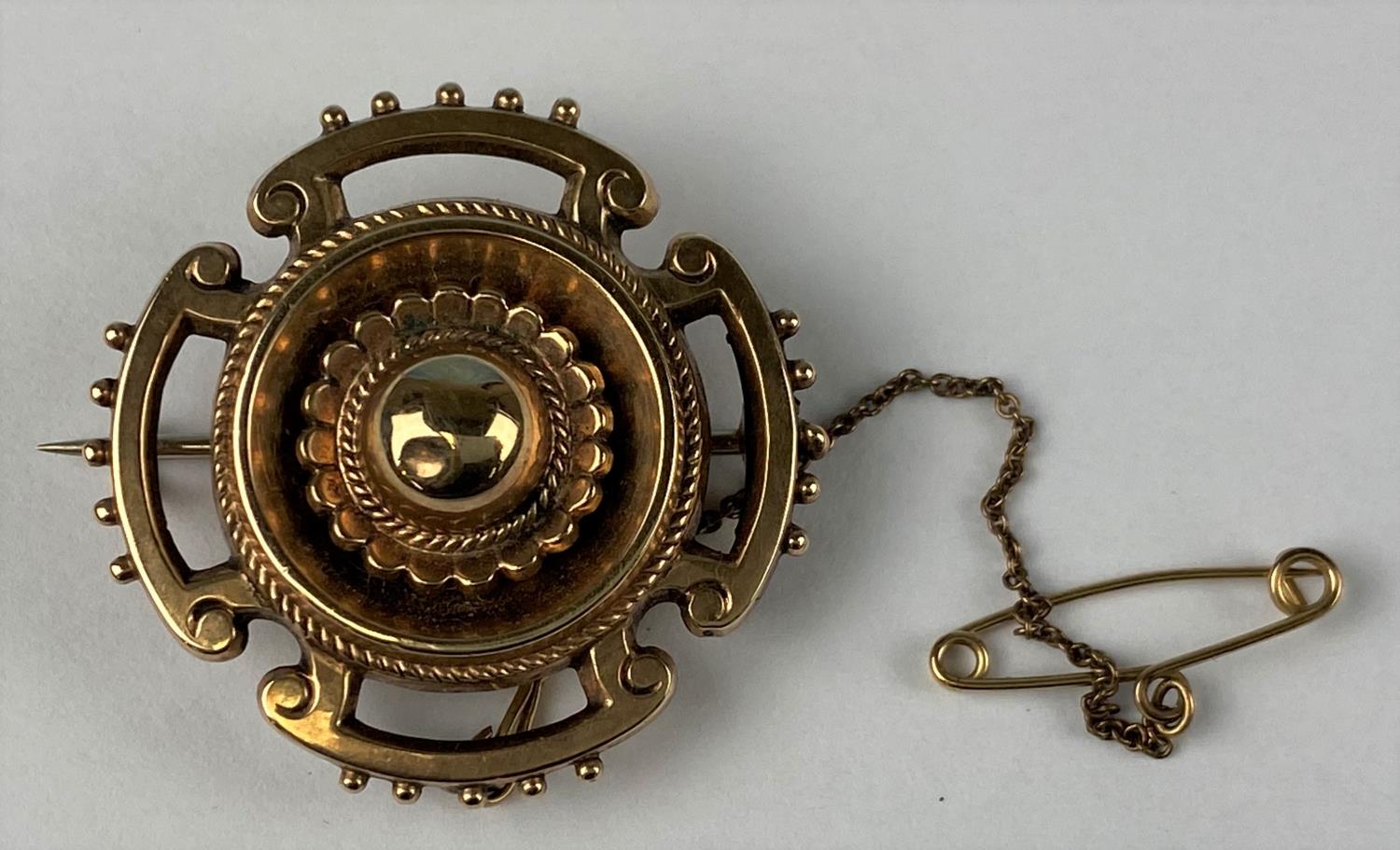 A round Victorian target brooch with fancy decoration supporting four cut out sections, bobbled