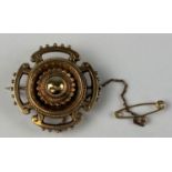 A round Victorian target brooch with fancy decoration supporting four cut out sections, bobbled