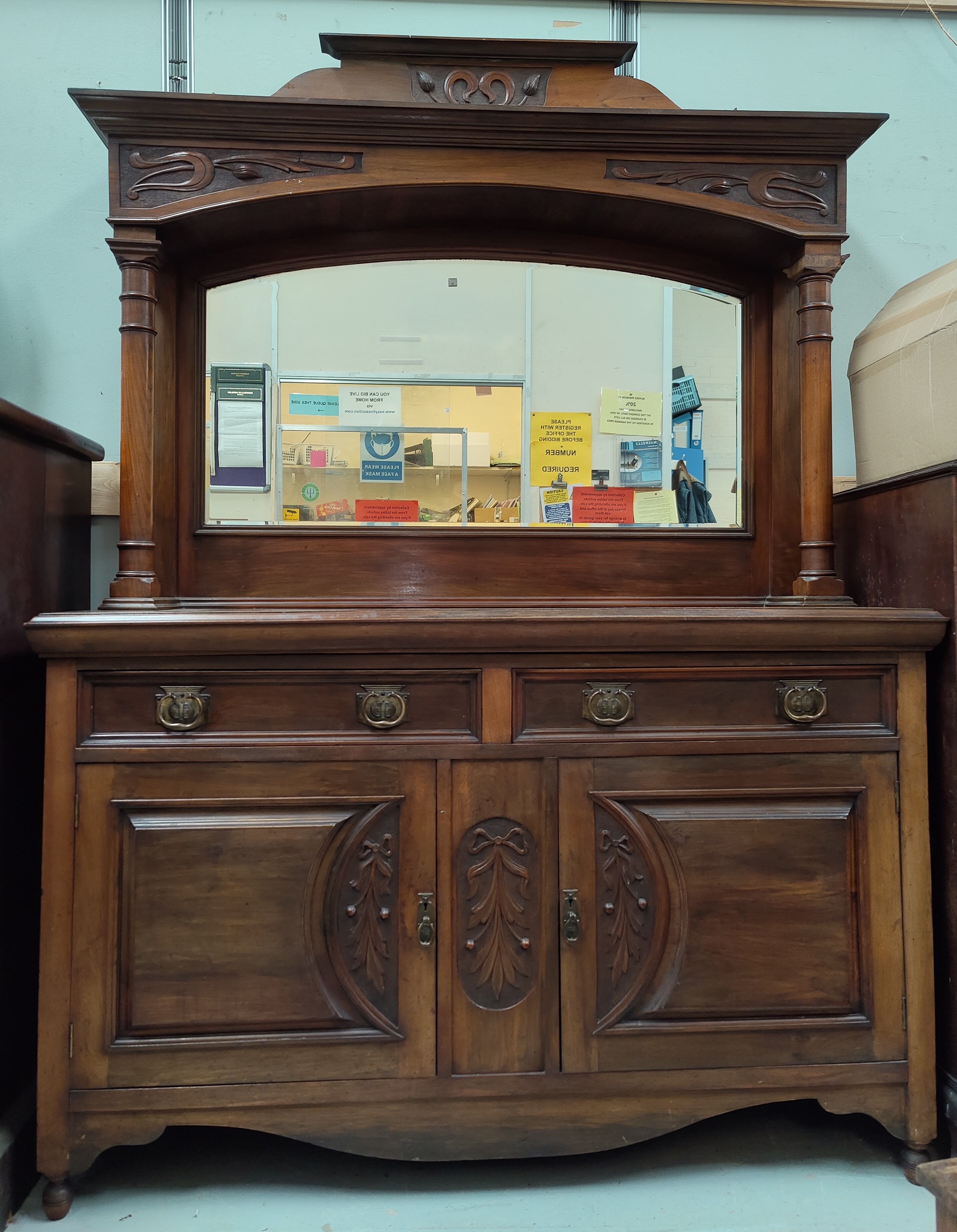 An Edwardian Art Nouveau carved walnut sideboard the mirror back with full turned side pillars,