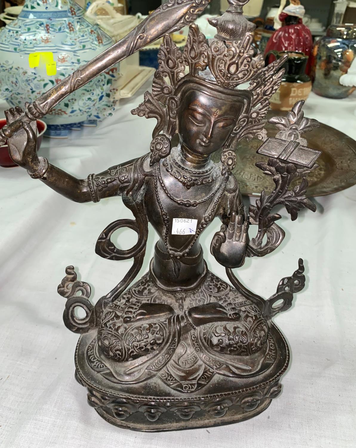 A Tibetan bronze figure of seated buddha with raised sword in one hand, seated in prayer position