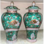 A pair of Chinese green ground lidded baluster vases with dragon decoration lids bearing marks,