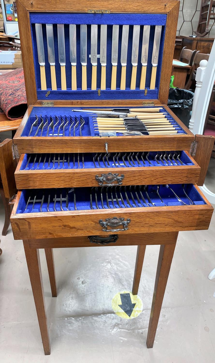 An Oak canteen on stand of silver plated cutlery with hinged lid, drawers below