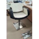 A vintage barber's chair in black and cream leather effect on swivel rise and fall frame and brushed