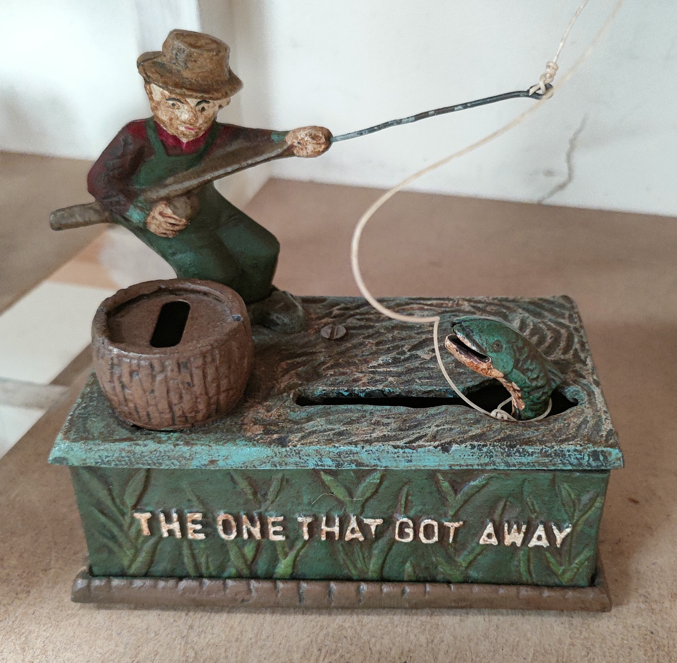 A vintage American cast iron money box with painted decoration "The One That Got Away" 17cm