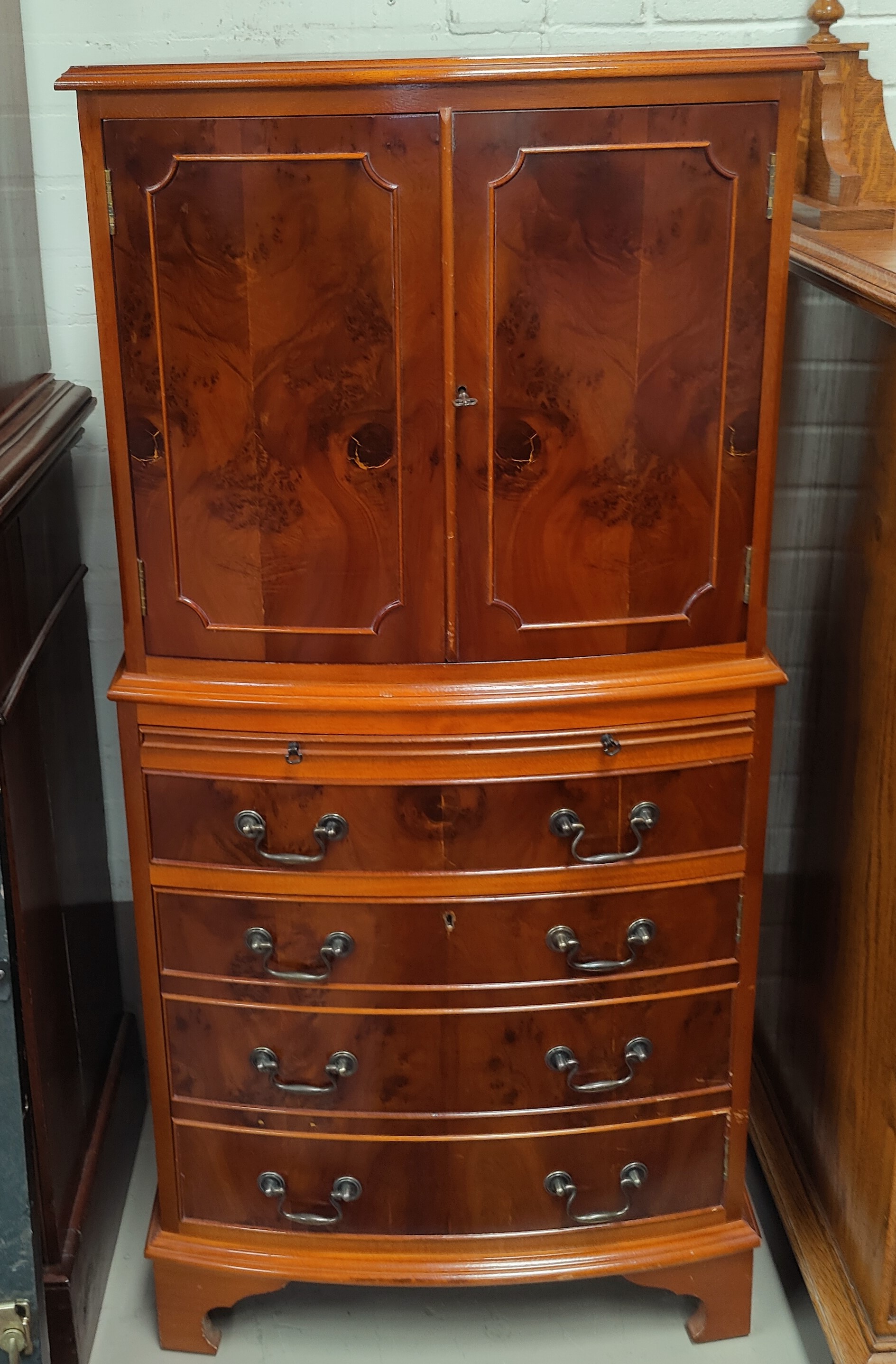 A reproduction Yew wood drinks cabinet in the form of cupboard on chest with double cupboard and 4