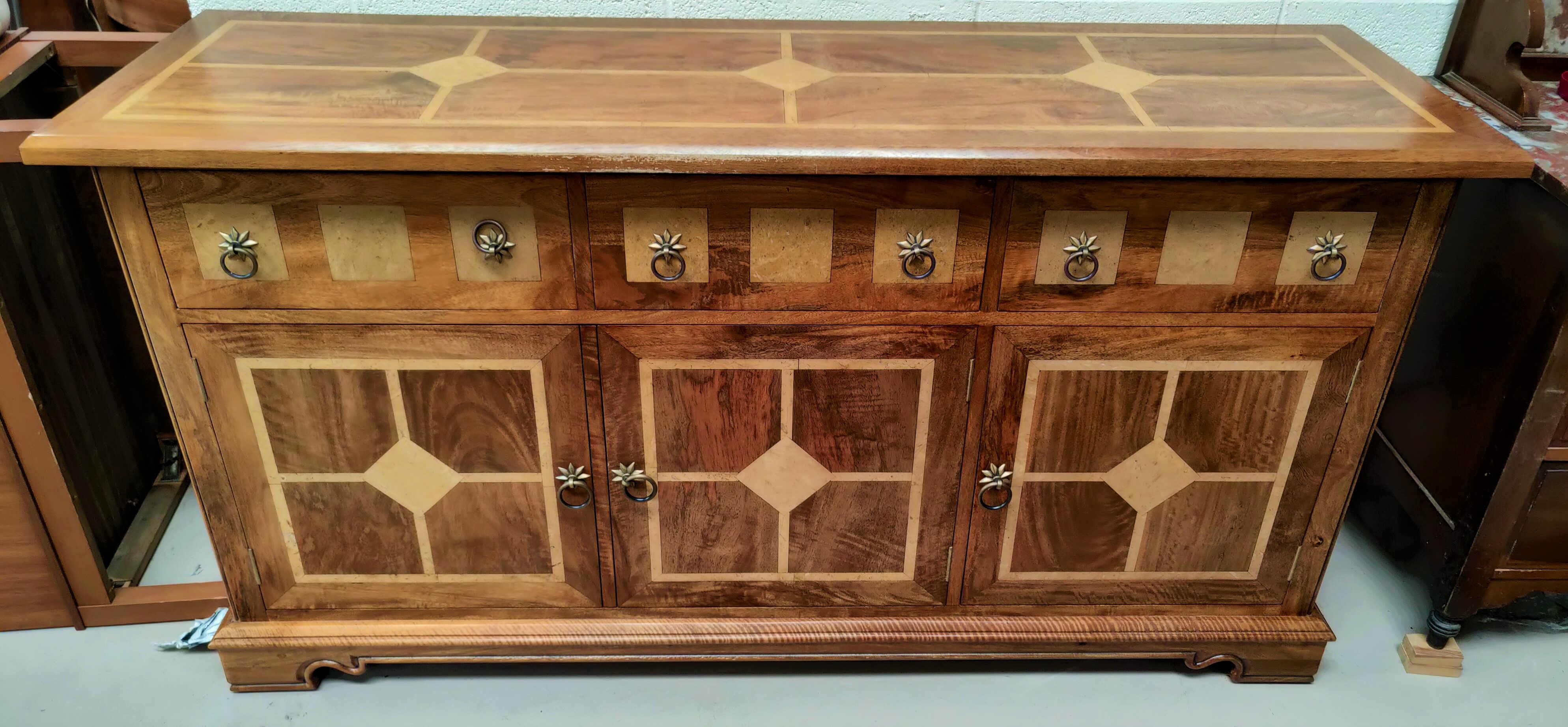 A modern lightwood sideboard with three cupboards and three drawers with inset marble effect