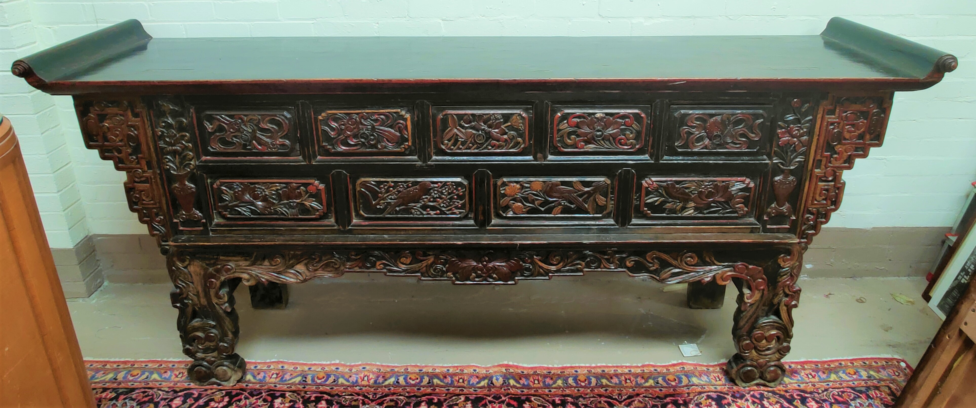 A late 19th/early 20th century Chinese unusual altar table, carved and lacquered with scroll end