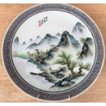 A 20th century Chinese hand painted charger decorated with mountain scenes, with text to top, seal