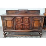 A 1930's William & Mary style carved oak sideboard of 2 cupboards and 2 central drawers