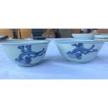 A matching pair of antique Chinese blue and white bowls with mythical creatures to the outside and