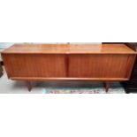 A 1960's teak low-line sideboard by Bernhard Pedersen, Denmark with 2 tambour doors enclosing