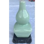 A Chinese celadon glaze double gourd vase with squared base, on wood stand, 6 character mark to