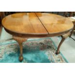 A walnut dining table with oval extending top on cabriole legs and ball and claw feet, 1 leaf,