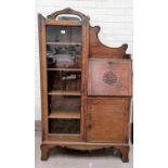 A 1930's oak side by side display cabinet with full length glazed door, cupboard and fall front
