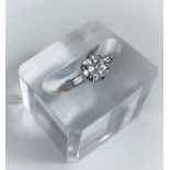 A diamond set ring with central bright cut stone and small baguette cut stone to either shoulder, on