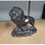 A painted bronze depicting a lion on a rock length 36cm