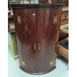 A Georgian mahogany corner cupboard with bow front enclosed by 2 doors