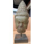 A large south east Asian Khmer style carved stone Buddha head on stand, height 42cm