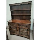 A carved oak reproduction Welsh dresser with 2 height delft rack over 2 drawers and 2 cupboards
