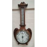 An Edwardian carved oak aneroid barometer and thermometer