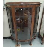 A 1930's walnut display cabinet enclosed by coloured leaded glass doors