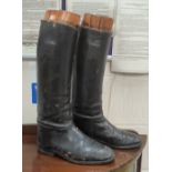 A pair of vintage knee high leather riding boots with wooden shapers inside.