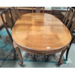 An oval walnut extending dining table with 1 spare leaf, extended length 180cm and set of four